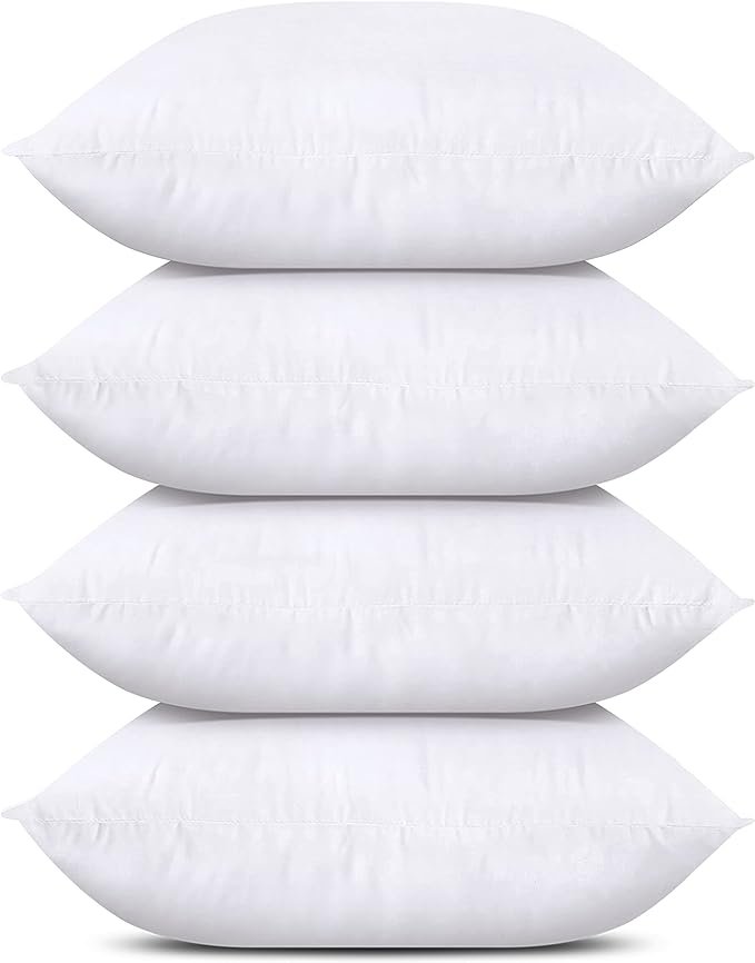 Four white pillows arranged neatly on a bed. The pillows are evenly spaced and feature a crisp, clean appearance, adding a fresh and inviting look to the bedding