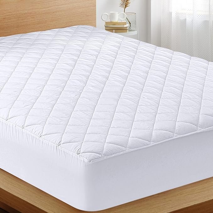 "White mattress with a smooth, clean surface and a simple, classic design. The mattress is positioned on a neutral-colored bed frame and is surrounded by a minimalistic bedroom setting."